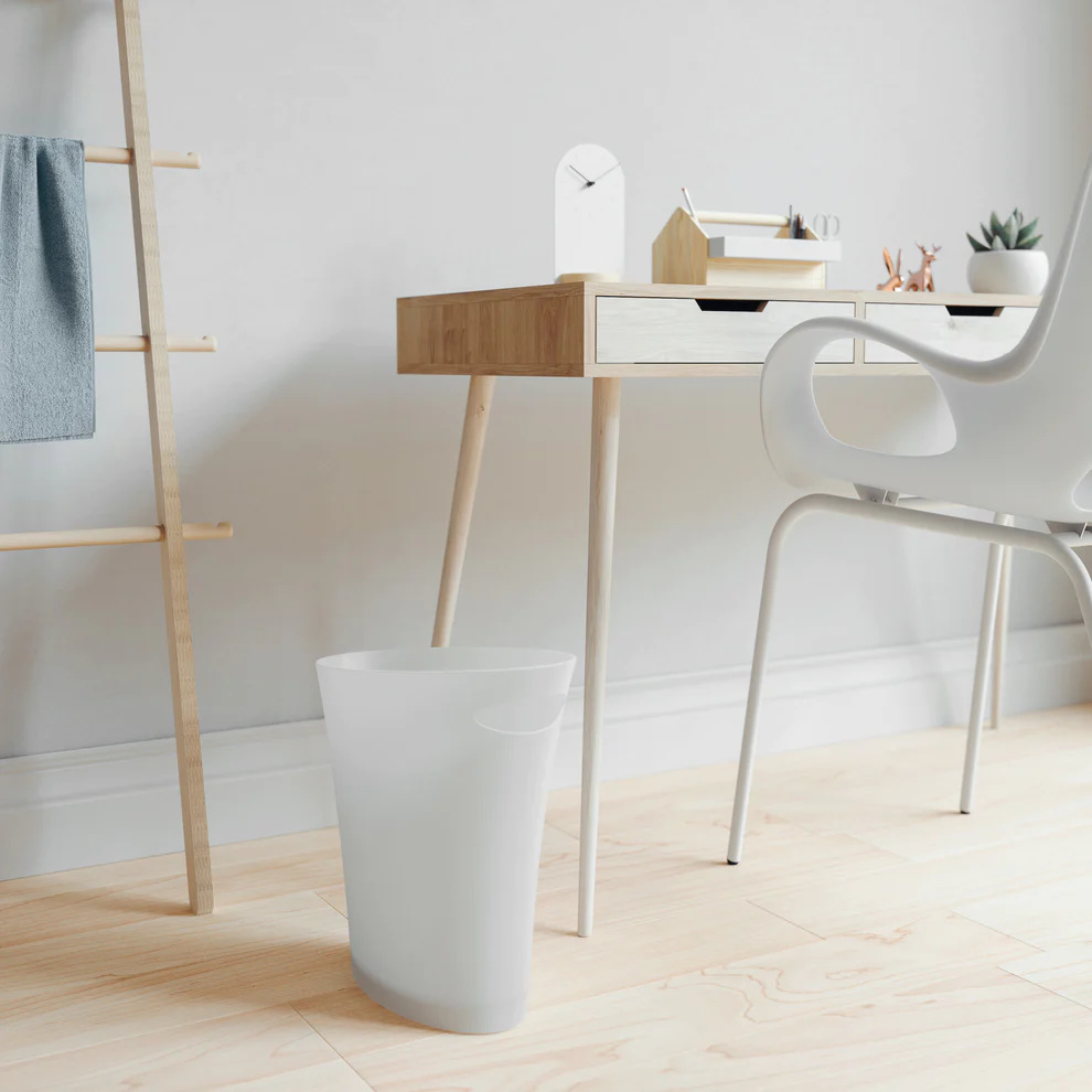 White skinny trash can by Umbra, shown next to a wooden desk