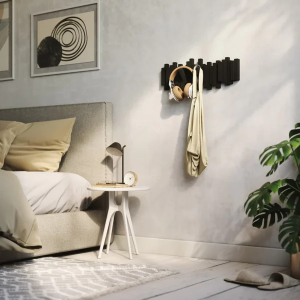 Black wall mount coat hook, shown on wall with headphones and bag