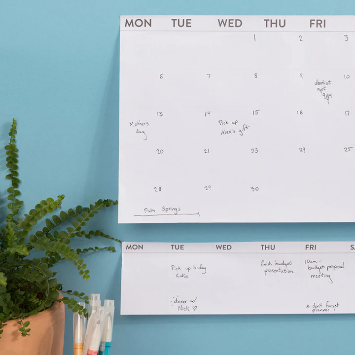 Weekly planner tear off pad shown on wall next to calendar