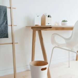 White Woodrow trash can shown next to wooden desk